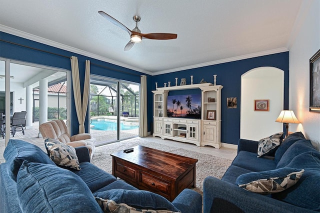 living room with ornamental molding, a ceiling fan, a sunroom, a textured ceiling, and baseboards