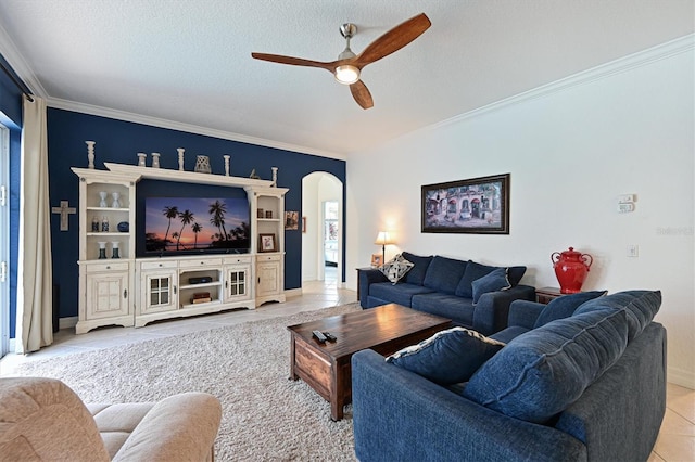 tiled living area featuring a ceiling fan, arched walkways, crown molding, and a textured ceiling