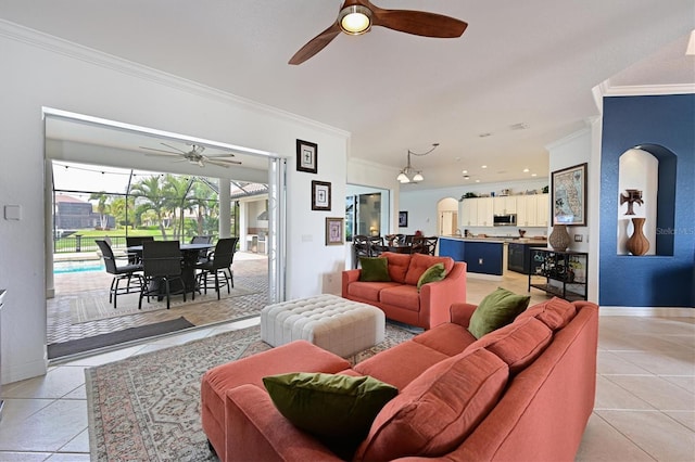 living room featuring light tile patterned floors, ceiling fan, baseboards, and crown molding