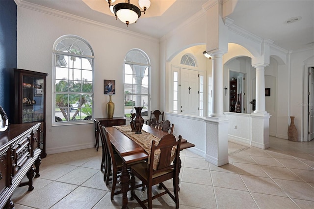 dining area with light tile patterned floors, baseboards, arched walkways, ornamental molding, and ornate columns