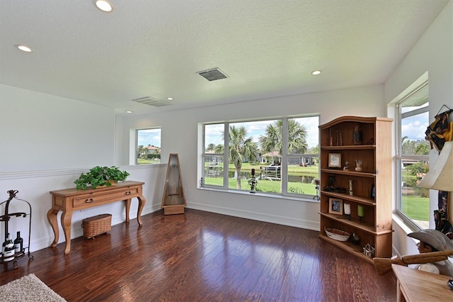 sitting room with a textured ceiling, dark wood finished floors, visible vents, and baseboards