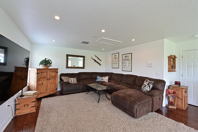 living room with a textured ceiling, dark wood-style flooring, visible vents, and recessed lighting