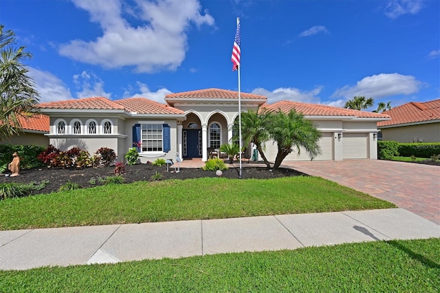 mediterranean / spanish-style house with a garage, a tile roof, decorative driveway, a front lawn, and stucco siding