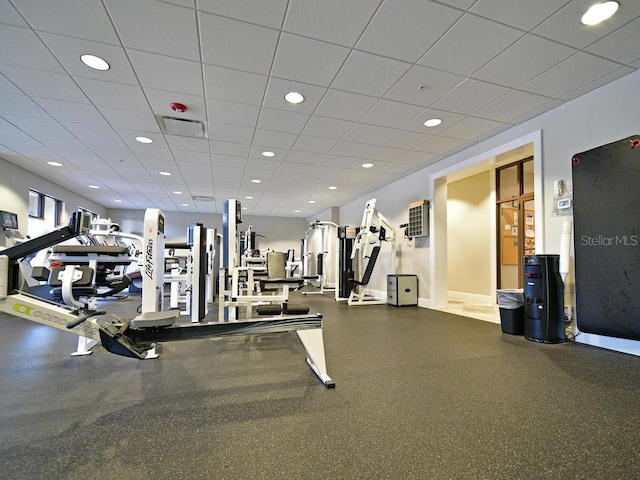 exercise room featuring baseboards, a paneled ceiling, and recessed lighting