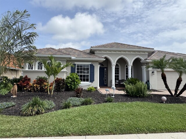 10509 Winding Stream Way, Bradenton, FL 34212 - mediterranean / spanish house featuring an attached garage, a porch, a front lawn, stucco siding, and a tile roof
