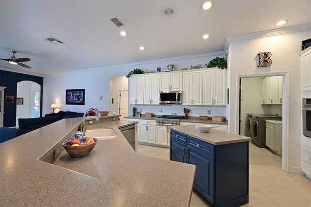 10509 Winding Stream Way, Bradenton, FL 34212 - kitchen with appliances with stainless steel finishes, arched walkways, a sink, a kitchen island, and ornamental molding