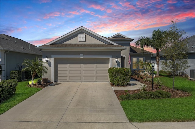 single story home with a garage, driveway, a front lawn, and stucco siding