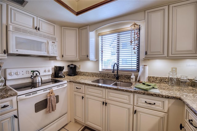 kitchen featuring white appliances, visible vents, a sink, and cream cabinets