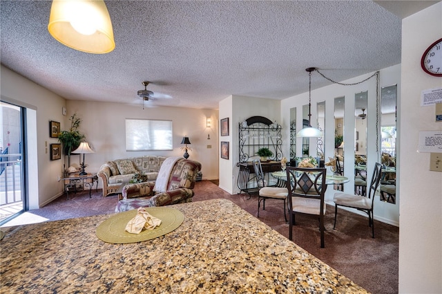 carpeted living area featuring baseboards, a ceiling fan, and a textured ceiling