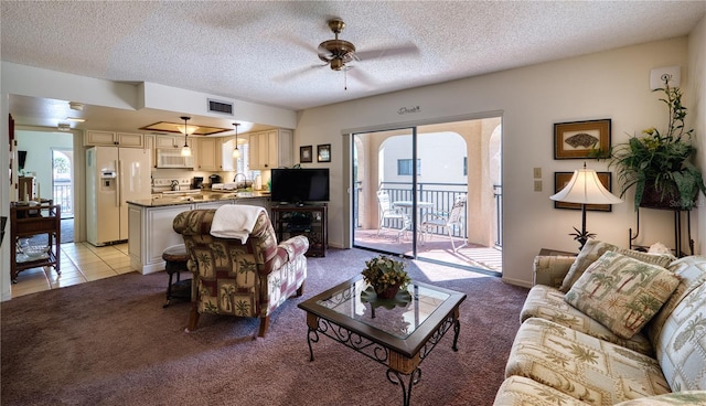 living room with light carpet, a healthy amount of sunlight, visible vents, and a textured ceiling