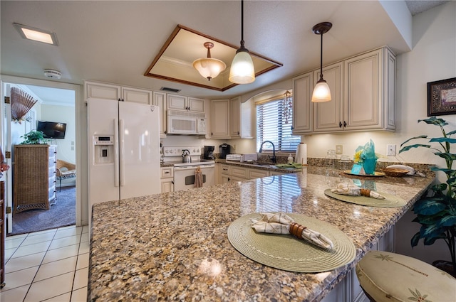 kitchen featuring dark stone counters, white appliances, a raised ceiling, and a peninsula