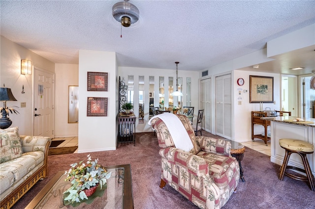 living area with light tile patterned floors, a textured ceiling, light carpet, and visible vents