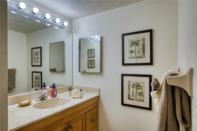 bathroom with a textured wall, a textured ceiling, and vanity