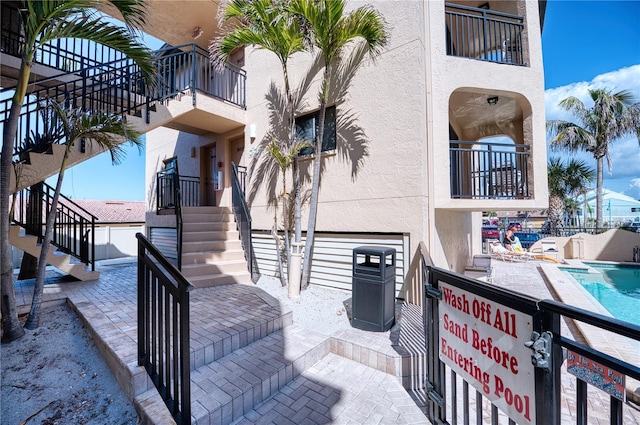 view of patio with a community pool and stairway