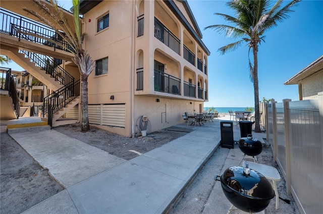 view of building exterior with a water view, fence, and stairs