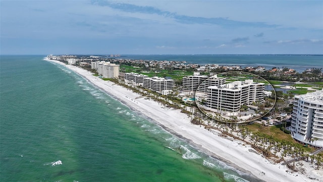 drone / aerial view featuring a water view, a view of the beach, and a city view