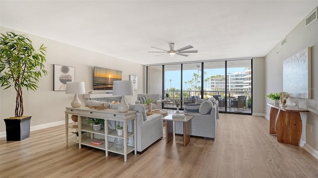 living area with floor to ceiling windows, visible vents, baseboards, and wood finished floors