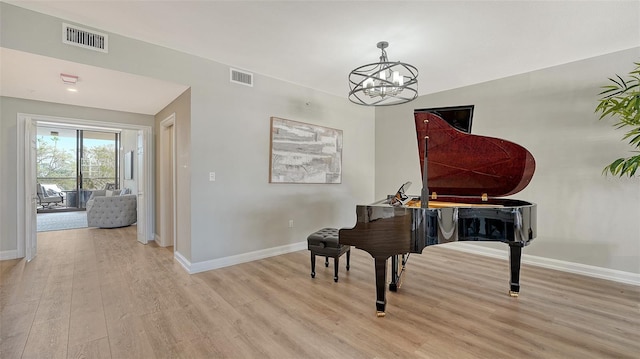 living area with an inviting chandelier, wood finished floors, visible vents, and baseboards