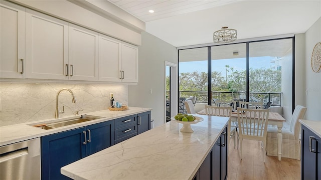 kitchen featuring light stone counters, backsplash, light wood-style floors, a sink, and dishwasher