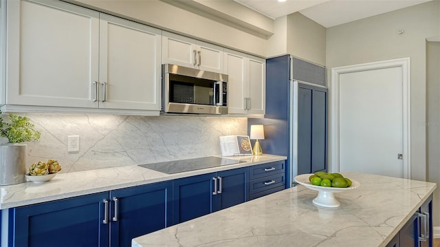 kitchen with blue cabinets, tasteful backsplash, stainless steel microwave, and black electric cooktop