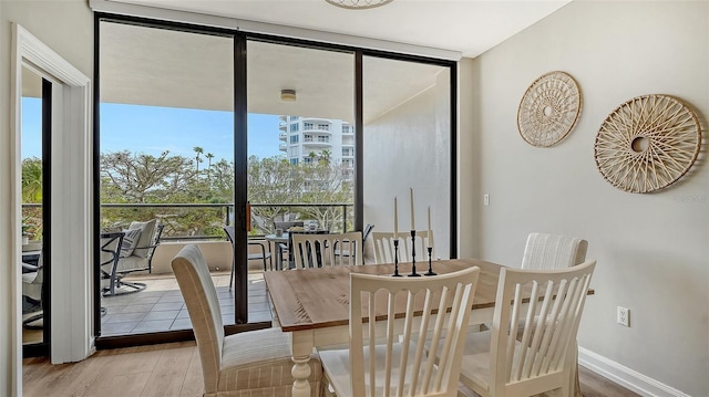 dining room featuring a wall of windows, wood finished floors, and baseboards