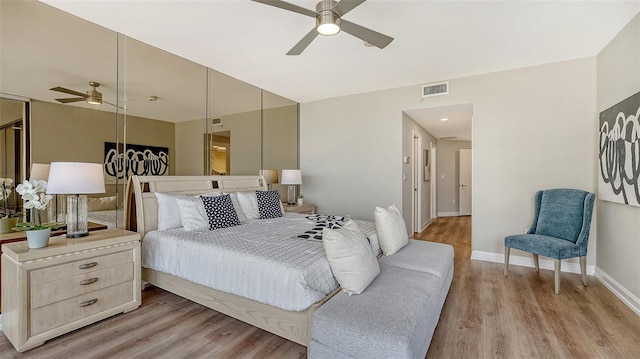 bedroom featuring ceiling fan, light wood-style flooring, visible vents, and baseboards