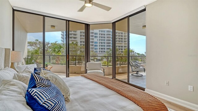 bedroom with access to exterior, a ceiling fan, wood finished floors, a wall of windows, and baseboards