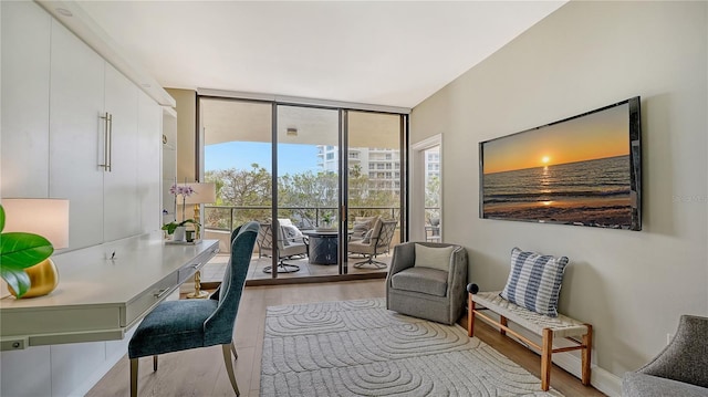 office area with expansive windows, baseboards, and light wood finished floors