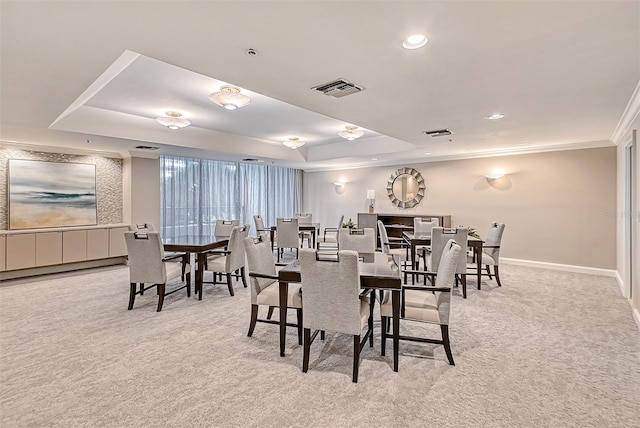 dining area featuring light carpet, visible vents, baseboards, a raised ceiling, and crown molding