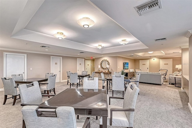 dining room featuring light carpet, visible vents, and a raised ceiling