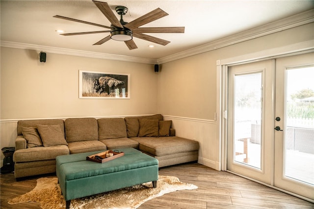 living area featuring french doors, a wainscoted wall, crown molding, and light wood-style flooring