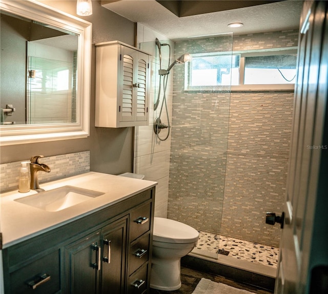 full bath featuring vanity, tasteful backsplash, tiled shower, and toilet