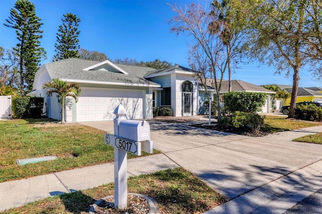 ranch-style home featuring stucco siding, a shingled roof, concrete driveway, an attached garage, and a front lawn