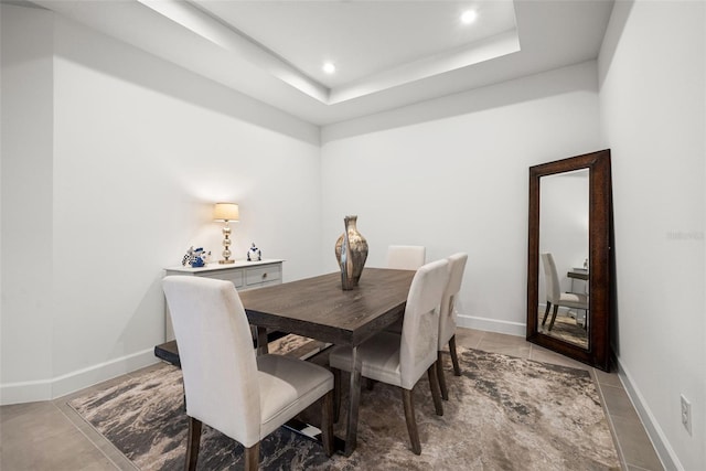 tiled dining space with a raised ceiling