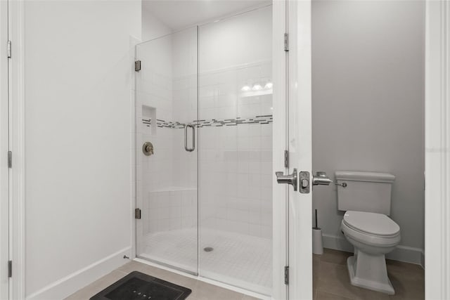 bathroom featuring tile patterned floors, toilet, and a shower with door