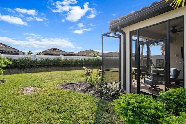 view of yard featuring a sunroom and ceiling fan