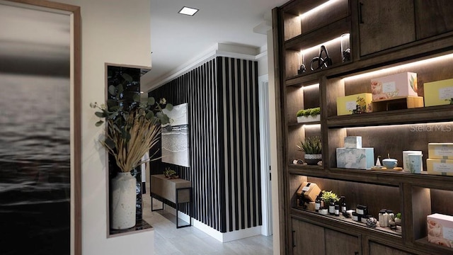 bar with light hardwood / wood-style floors, dark brown cabinetry, and built in features