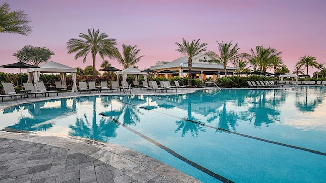 pool at dusk featuring a patio area and a gazebo