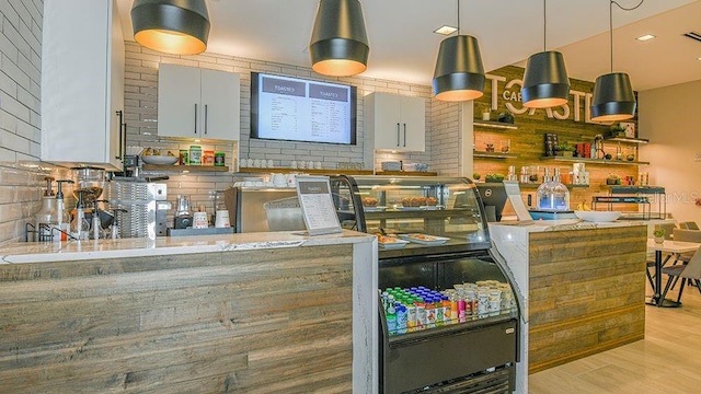 kitchen featuring light wood-type flooring, pendant lighting, backsplash, and kitchen peninsula