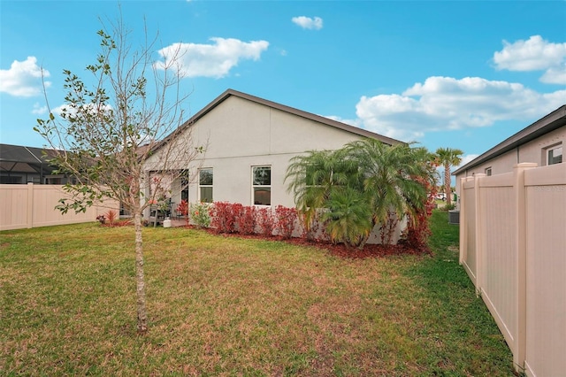 view of side of home featuring a lawn, a fenced backyard, and stucco siding