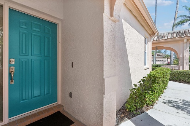 doorway to property with a tiled roof and stucco siding