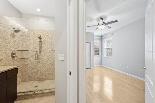 full bathroom with a stall shower, ceiling fan, baseboards, and wood finished floors