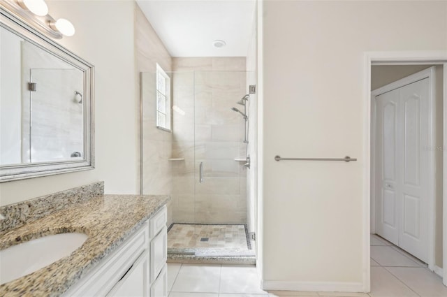 bathroom featuring vanity, baseboards, a closet, a shower stall, and tile patterned floors