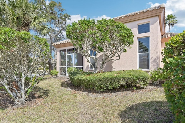 view of home's exterior featuring a yard, a tile roof, and stucco siding