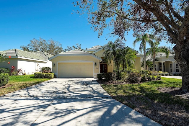 view of front of property featuring concrete driveway, a front lawn, an attached garage, and stucco siding