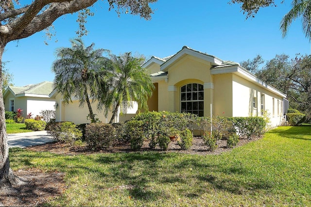 view of front of property with a garage, concrete driveway, a front yard, and stucco siding