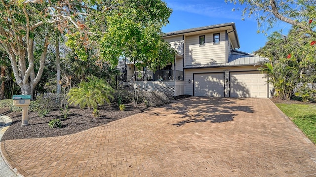 view of front of house featuring decorative driveway, covered porch, an attached garage, a standing seam roof, and metal roof