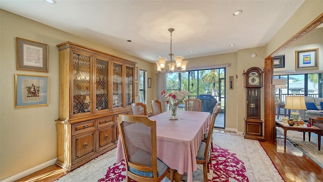 dining room with a textured ceiling, recessed lighting, wood finished floors, baseboards, and an inviting chandelier