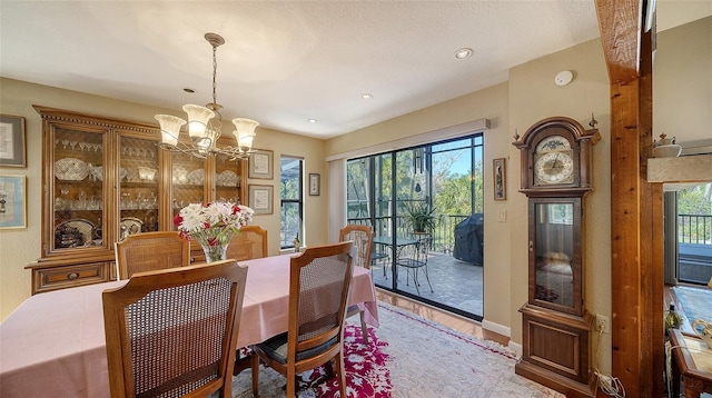 dining space with a chandelier, plenty of natural light, a textured ceiling, and wood finished floors