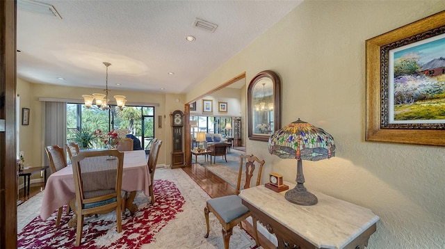 dining space with visible vents, a textured wall, light wood-style flooring, a textured ceiling, and a notable chandelier